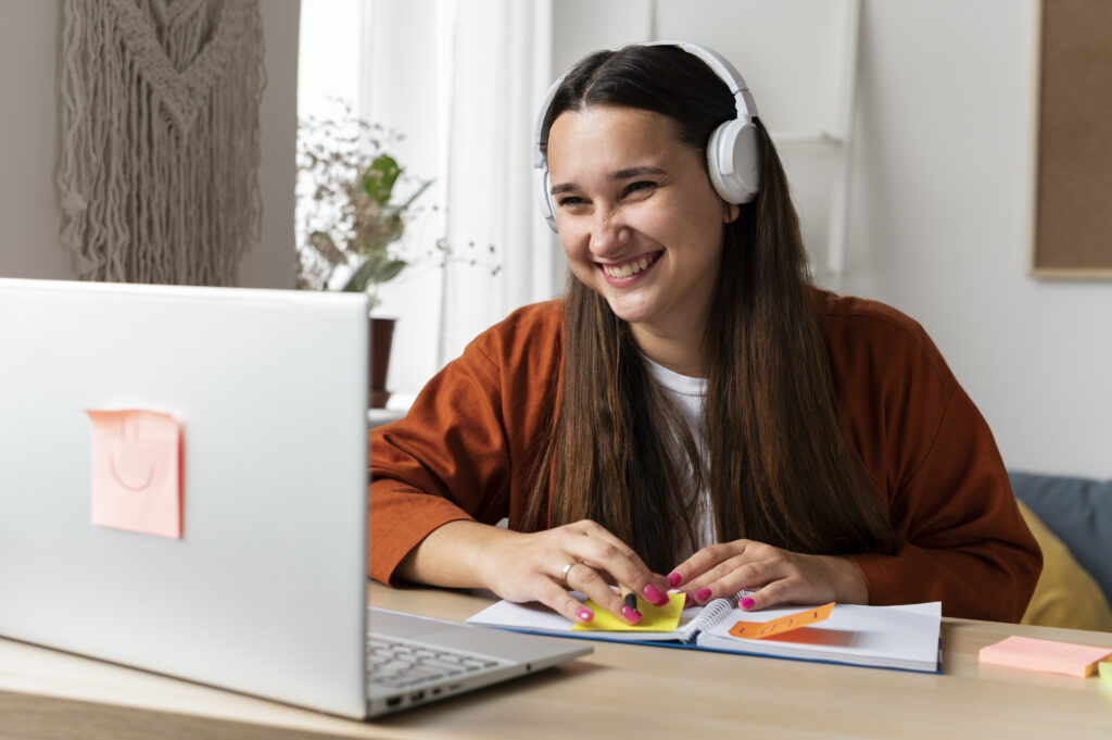 Mulher sorrindo enquanto participa de uma mentoria online pelo computador.
